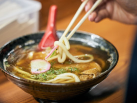 Steam rising from bowls of ramen at a late-night street cart.