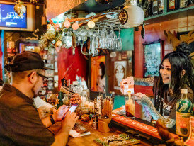 Bartender serving drinks in tiny establishment. 
