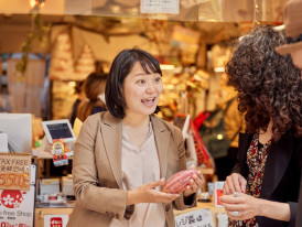 Host guiding small group through market pointing out seasonal ingredients.