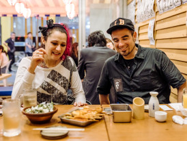 Guest-host conversation at table sharing stories over meal.