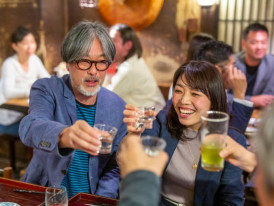 Craft beer and sake glasses mid-toast between guests. Image by davidf