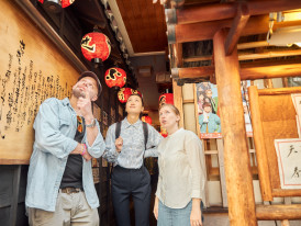 Host pointing out non-obvious signboard hidden in alleyway.