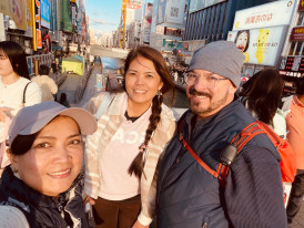 Travelers taking a candid photo with their host at sunset.