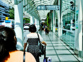 A traveler with luggage confidently navigating the modern, well-signaged arrivals area of Kansai International Airport. Image by Cheesum Hoo on Unsplash.