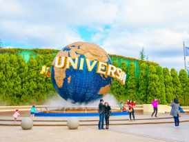 The iconic entrance to Universal Studios Japan with its distinctive globe landmark and excited visitors entering the park. 