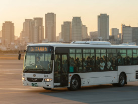 Airport bus departing Itami with Osaka skyline in background.