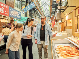 Vendor displaying fresh tuna cuts at Kuromon Market.