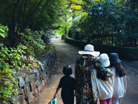 A family walks toward the main gate of Tennoji Zoo on a clear day, surrounded by trees and signage. Image by Juan Lizardo on Unsplash.