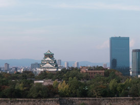 Osaka Castle seen from afar, framed by trees and buildings in the Tennoji area. Image by Tuan P. on Unsplash.