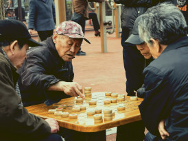 Local man focused on a game of shogi at a small table outside a kushikatsu shop in Shinsekai. Image by Woody Yan on Unsplash.