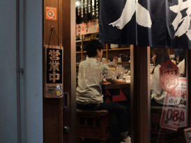 A regular customer shares a friendly conversation with the restaurant owner inside a cozy Shinsekai eatery. Images by Mak on Unsplash.