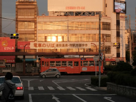 Street signs in Shinsekai glowing under golden hour light, casting a warm hue over the retro-style neighborhood scene. Image by Mak on Unsplash.