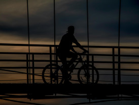 Cyclist crossing bridge at dusk photo Photo by alfian Pexels