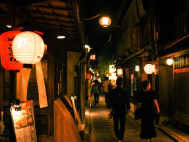 A small group walking through a quiet alley with traditional wooden buildings and lanterns.Photo by ayumi kubo on Unsplash