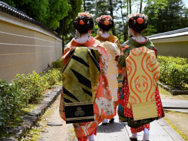 Geisha walking through Gion in Kyoto, wearing kimono and moving through historic streets.
