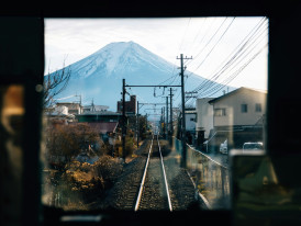 Traditional train traveling through Kyoto suburbs with mountains visible in the distance. Image by Peter Thomas from Unsplash