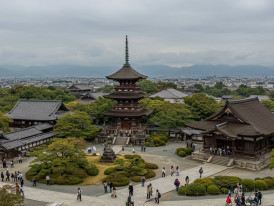 A panoramic view showing multiple temple complexes across Kyoto with visitors exploring different architectural styles