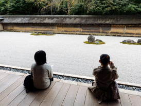Visitors sitting in contemplation viewing the Ryoan-ji rock garden from the wooden platform photo by r.nagy on shutterstock