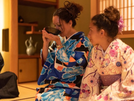 Traditional tea ceremony in progress with precise hand movements and seasonal arrangements