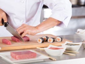 Sushi chef carefully preparing fish.