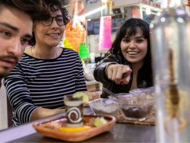 City Unscripted host and guests trying Mezcal from a bottle with a scorpion in Mercado de San Juan