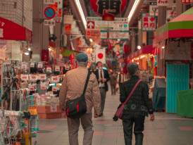 Exploring colorful stalls at Kuromon Market: Photo by Yuki: https://www.pexels.com/photo/woman-and-man-walking-on-bazaar-7695090/