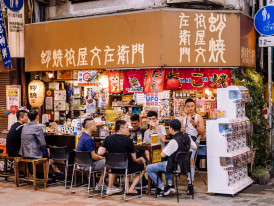 Busy Osaka street with locals chatting and laughing over food
