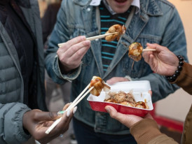 Person trying takoyaki in casual alley
