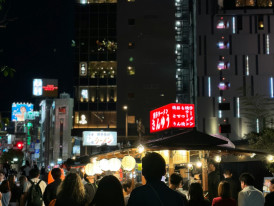 Host and traveler sharing street food under neon lights Photo by Caro Chui on Unsplash