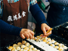 Takoyaki sizzling on a pan with chef's hands working the tools Photo by Markus Winkler on pexels