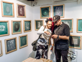 Close-up shot of a traveler and host having an intimate conversation while examining intricate details of a traditional craft at a small artisan workshop