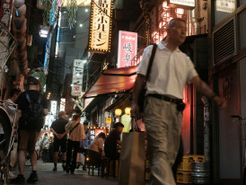 A narrow alley lined with small restaurants, their warm light spilling onto the street Photo by Perry Merrity II on Unsplash
