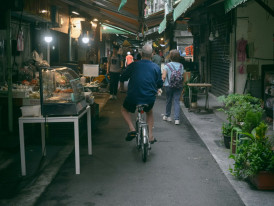 Cyclist riding through quiet residential street in Osaka with local shops and houses Photo by hayato togashi on Unsplash