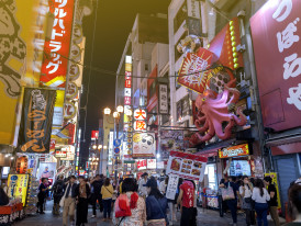 A busy market with vendors, shoppers, and visitors exploring food stalls. 