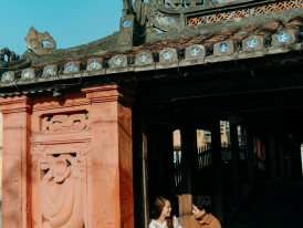 A guest and guide sharing a laugh while walking near a temple entrance. Photo by Trần Long on pexels