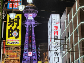 Tsutenkaku Tower surrounded by traditional shops and neon signs. Photo by Da-shika on Unsplash