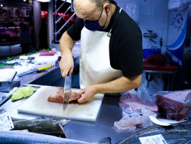 Tuna being expertly sliced at a market stall with customers watching. Photo by Scottish Skies on pexels
