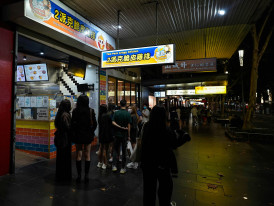 Food stalls near a busy train station with commuters and tourists. Photo by 1Click on Unsplash