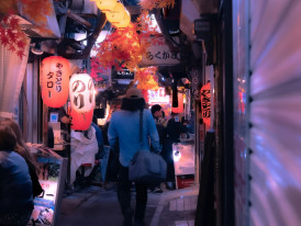 Narrow alley filled with glowing lanterns and tiny bars, host leading guest through Photo by mos design on Unsplash