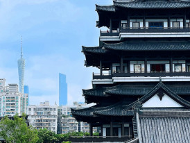 Traditional temple gate with modern city skyline visible in background. Photo by Kakohri H on Unsplash