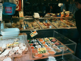 Clean and busy sushi counter with fresh fish displayed on ice and active preparation Photo by Alicja Podstolska on Unsplash