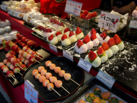 Festival food stalls with yakitori, chocolate bananas, and other festival snacks with festive lighting Photo by Marek Lumi on Unsplash