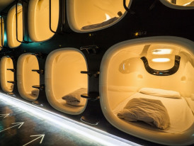 Modern capsule hotel interior showing individual sleeping pods with built-in entertainment systems.