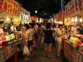 Colorful street food stalls at evening market with kakigōri shaved ice and traditional cooling treats.