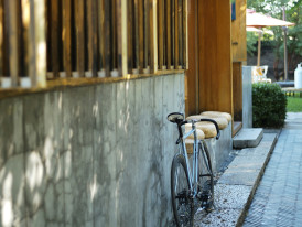 Traditional wooden house with modern bicycle parked outside, morning shadows creating patterns Photo by tommao wang on Unsplash