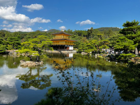 Traveler taking a photo at Kinkakuji with a host nearby Photo by Arash K on pexels