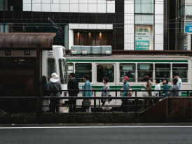 Passengers boarding a bus at a busy Kyoto intersection with traditional and modern buildings visible Photo by Christian Chen on Unsplash
