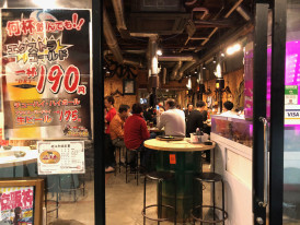 Busy izakaya counter with locals enjoying drinks and small plates.