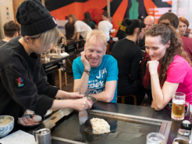 Local okonomiyaki restaurant with chef cooking on traditional griddle.