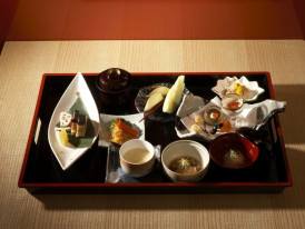 Artfully plated multi-course Japanese meal featuring fresh seasonal ingredients on lacquered trays